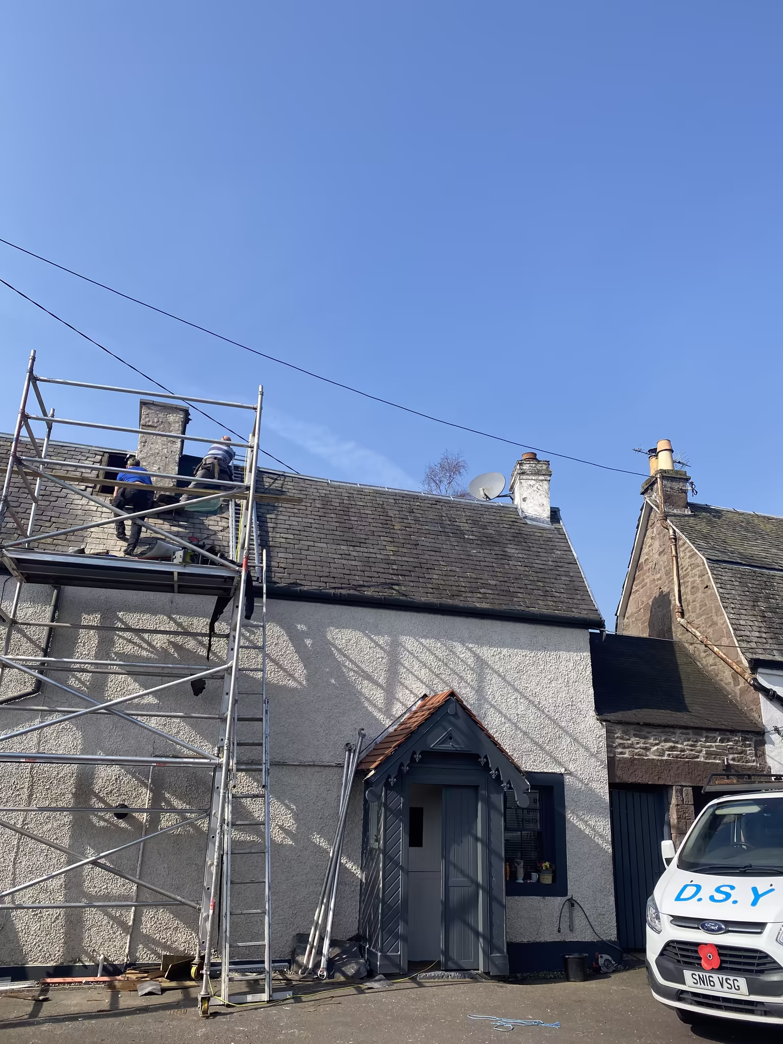 Scaffolding erected around a stone chimney stack for essential repointing and repair work