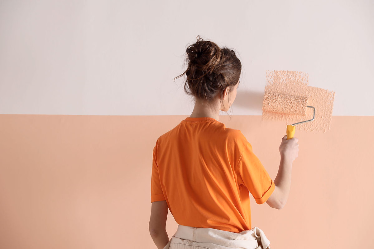 A woman applying a fresh coat of paint to a wall ahead of a roughcasting finish