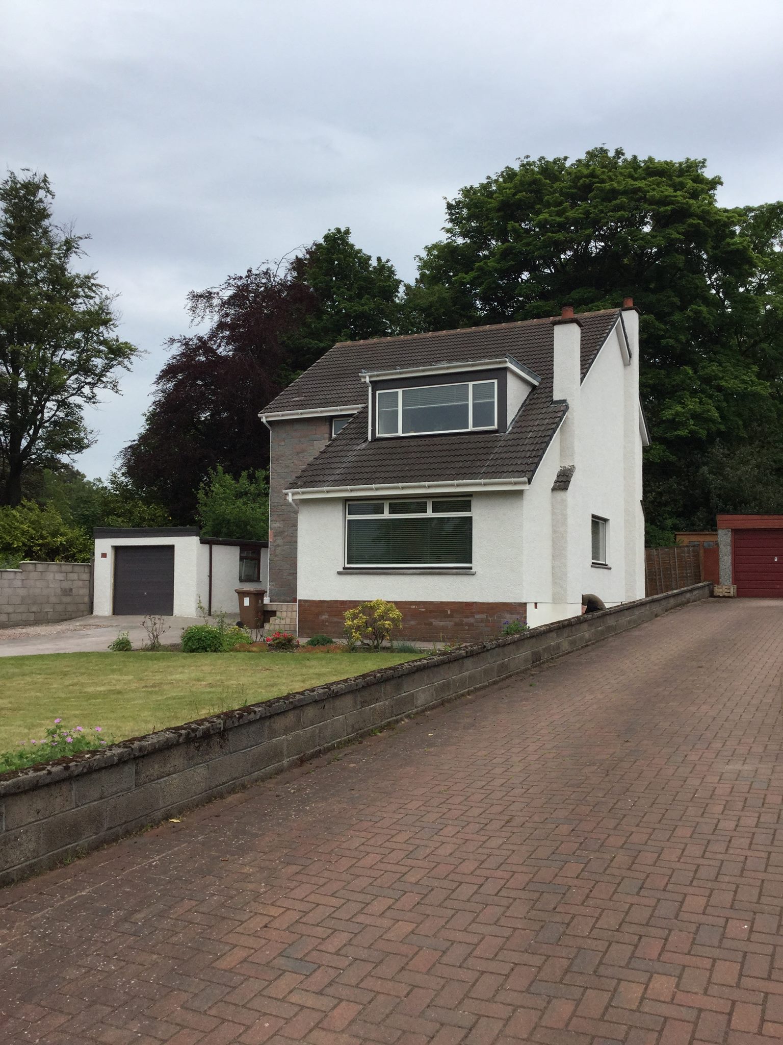 A traditional detached sandstone-built house with a driveway, prepared for exterior restoration work