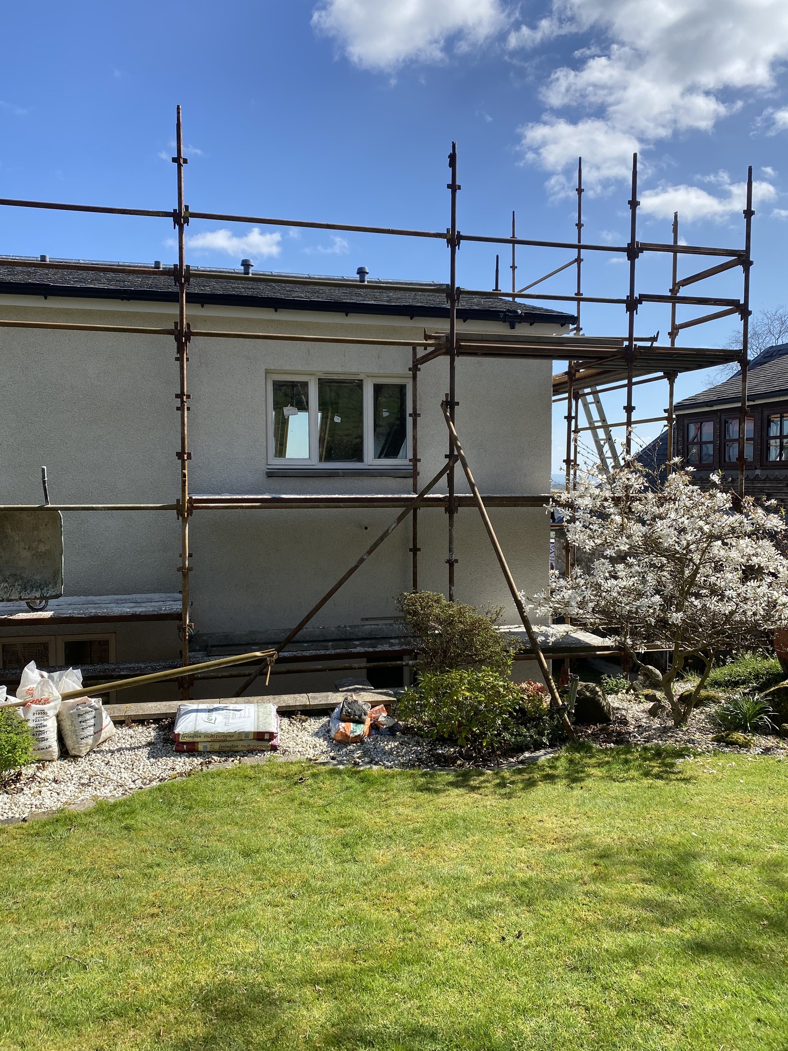 Scaffolding erected against a rendered house during sandstone restoration work