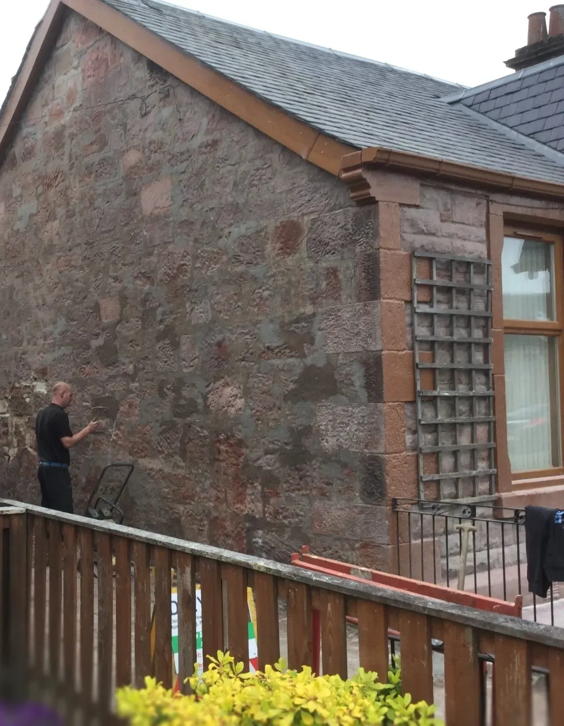A stonemason restoring the exterior sandstone wall of a heritage property