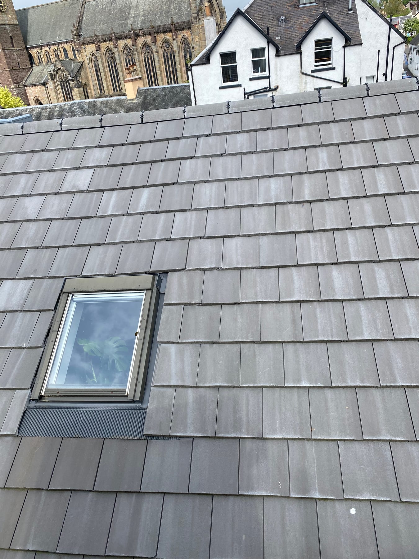 A Velux window fitted with flashing into a grey concrete tiled roof